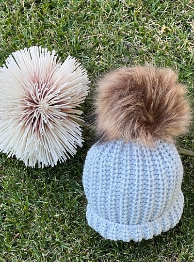 Gorrito de Bebé en punto gordito con pompón de pelo sintético.